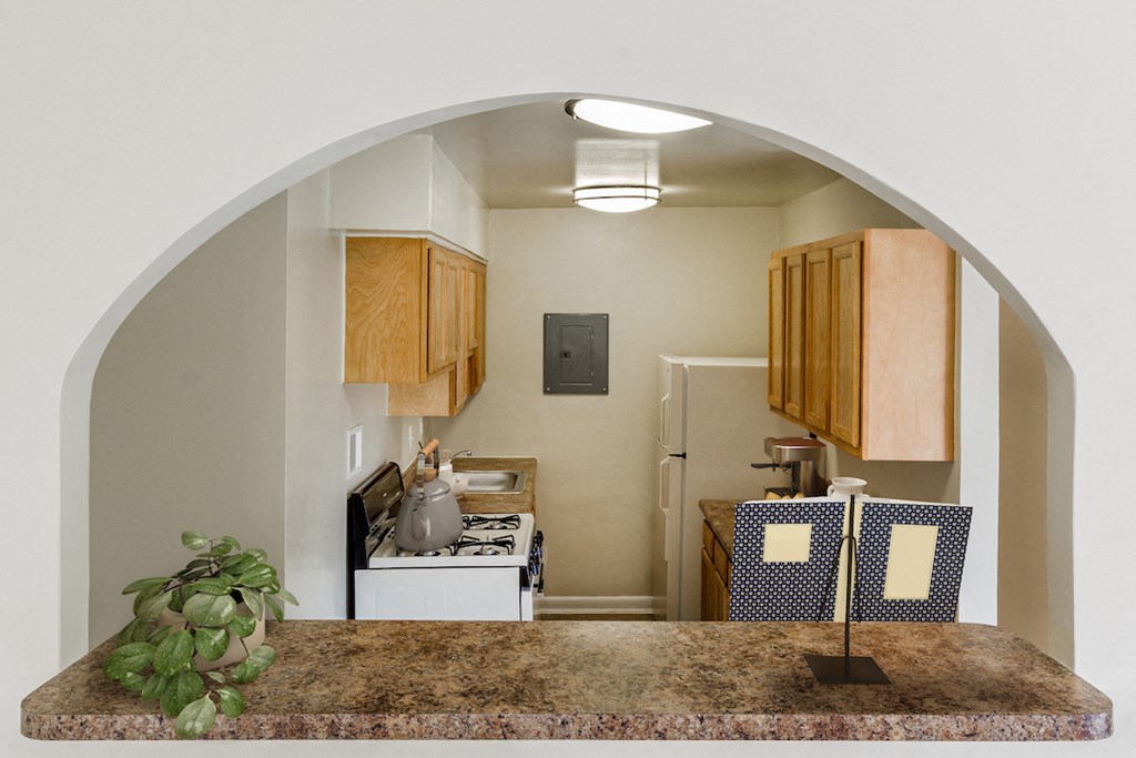 an arched doorway looking into a kitchen with a counter and a refrigerator
