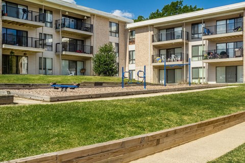 a playground in front of an apartment building with a blue bench