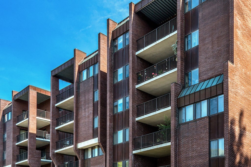 a tall brick building with balconies and a blue sky