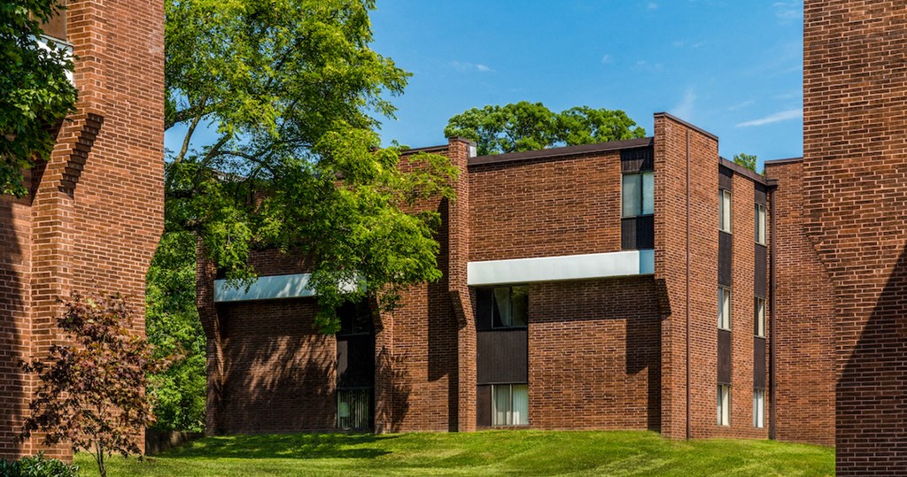 the exterior of a brick building with green grass and trees