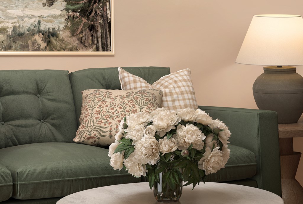 a living room with a green couch and a vase of flowers