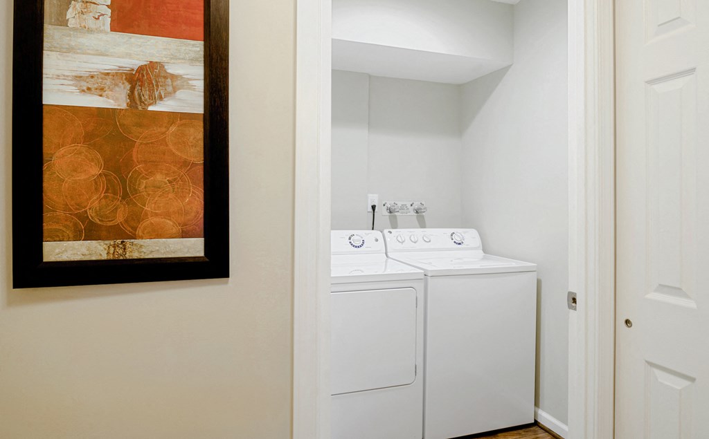 a washer and dryer in a small room with a painting on the wall