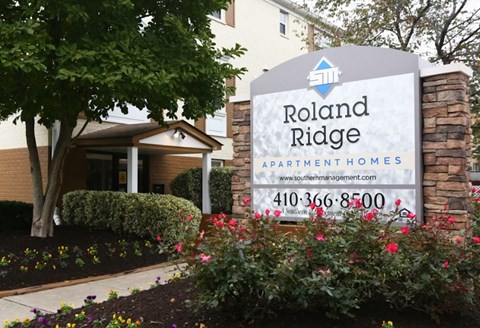 a building with a sign and flowers in front of it