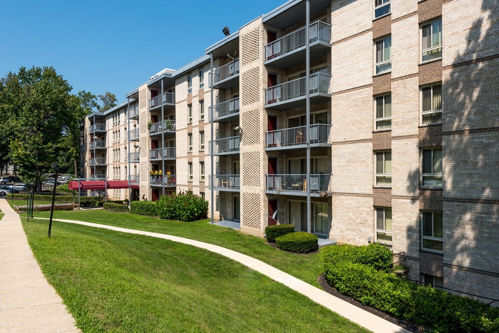 an exterior view of an apartment building with a sidewalk and grass