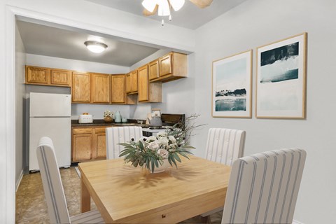 a dining room with a wooden table and chairs and a kitchen with a refrigerator