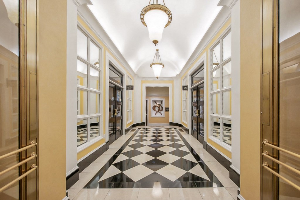 a hallway with a checkered floor and a chandelier