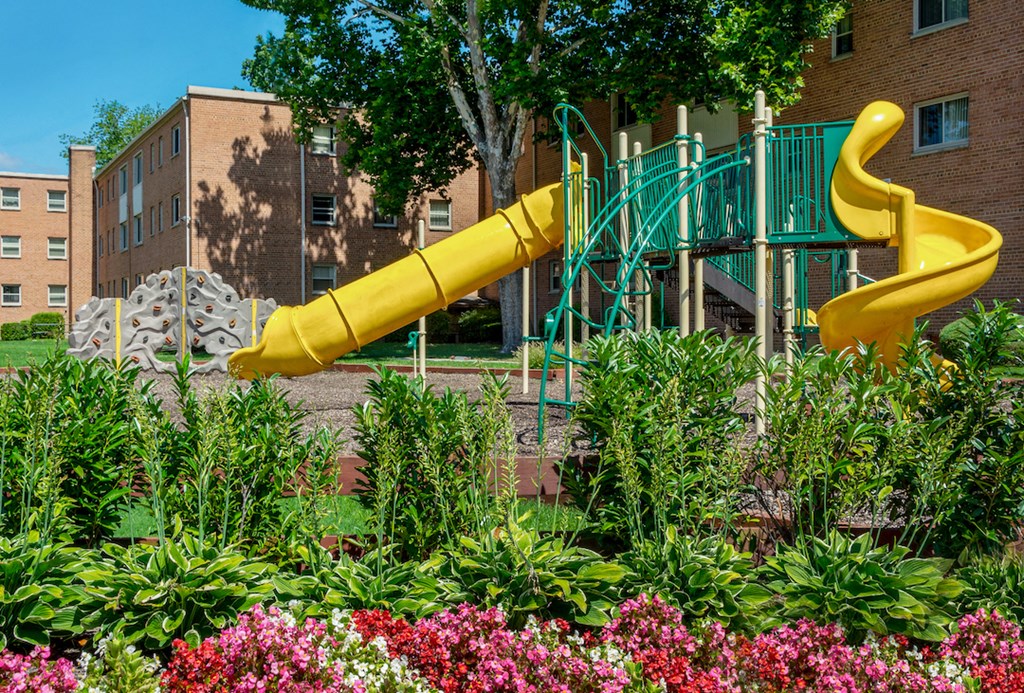 a large yellow slide in a playground in a garden