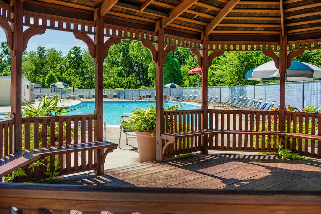 a gazebo with benches next to a swimming pool