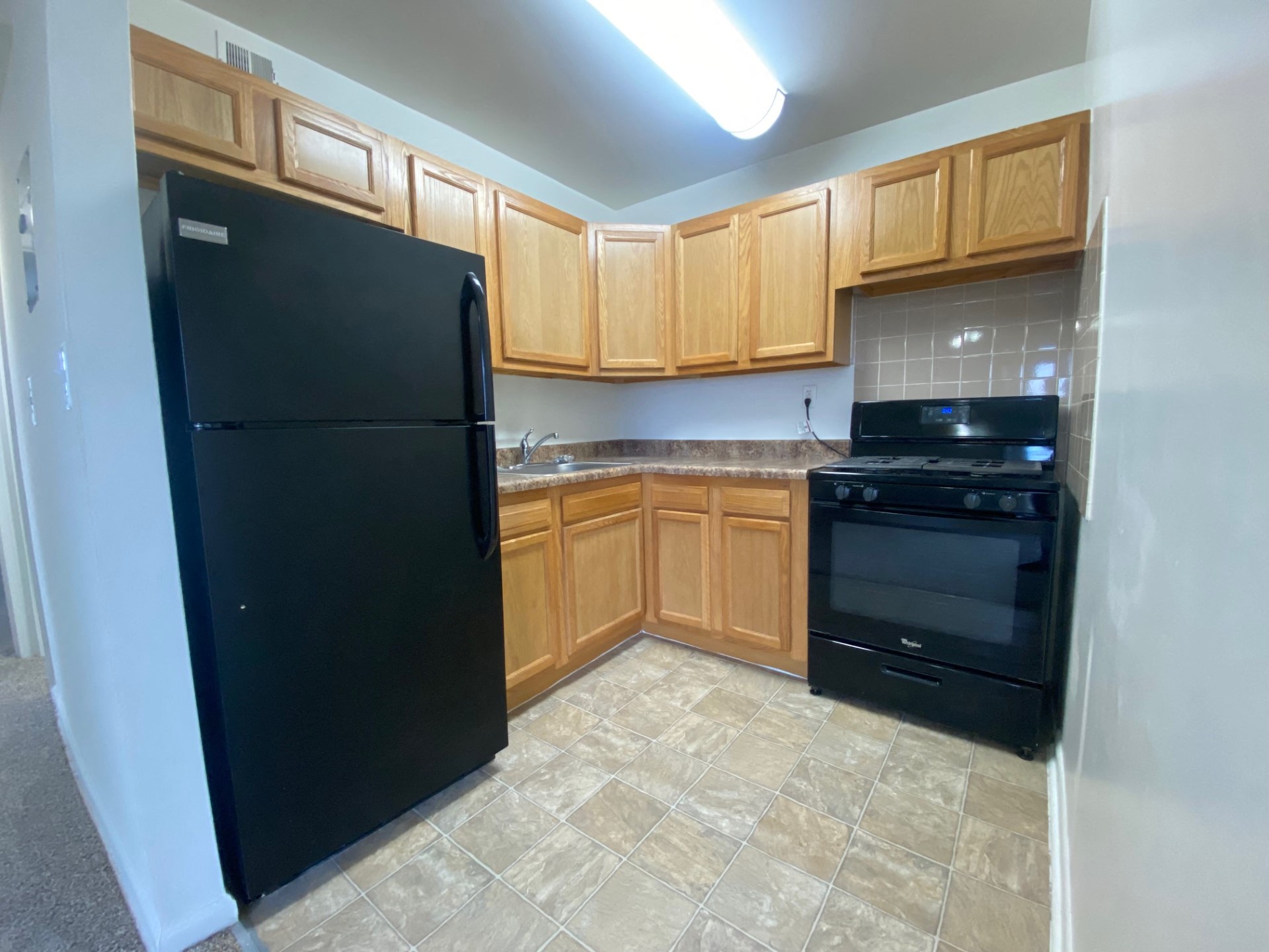 an empty kitchen with black appliances and wooden cabinets