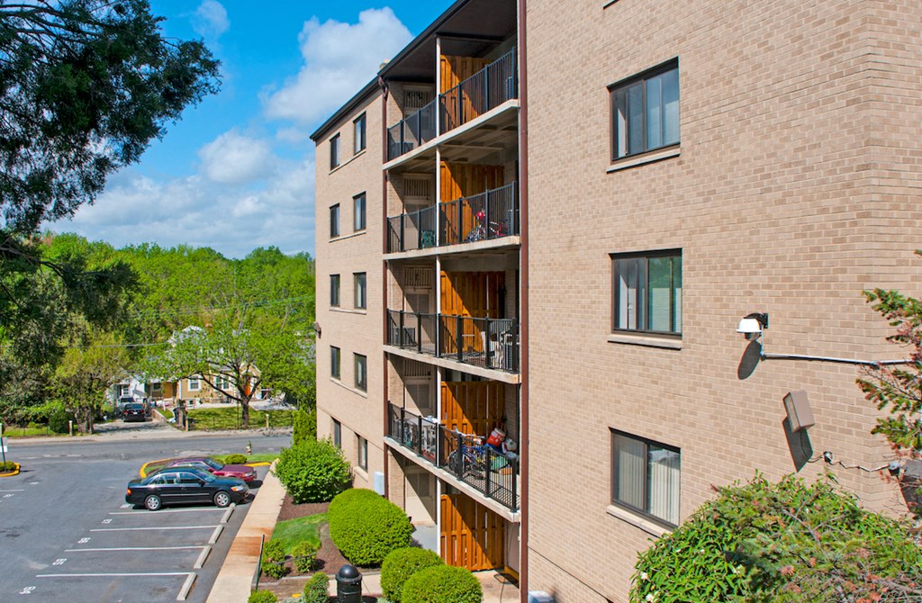 a brick apartment building with balconies and a parking lot