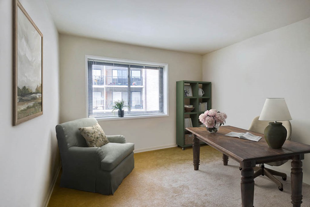 a living room with a desk and a chair and a window