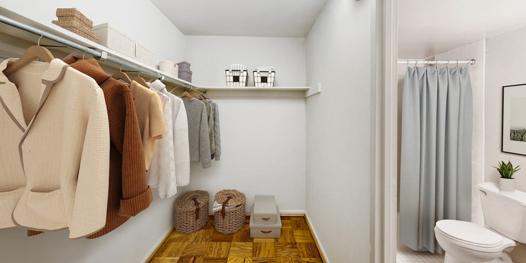 a small bathroom with a shower and a toilet and a closet with clothes hanging on