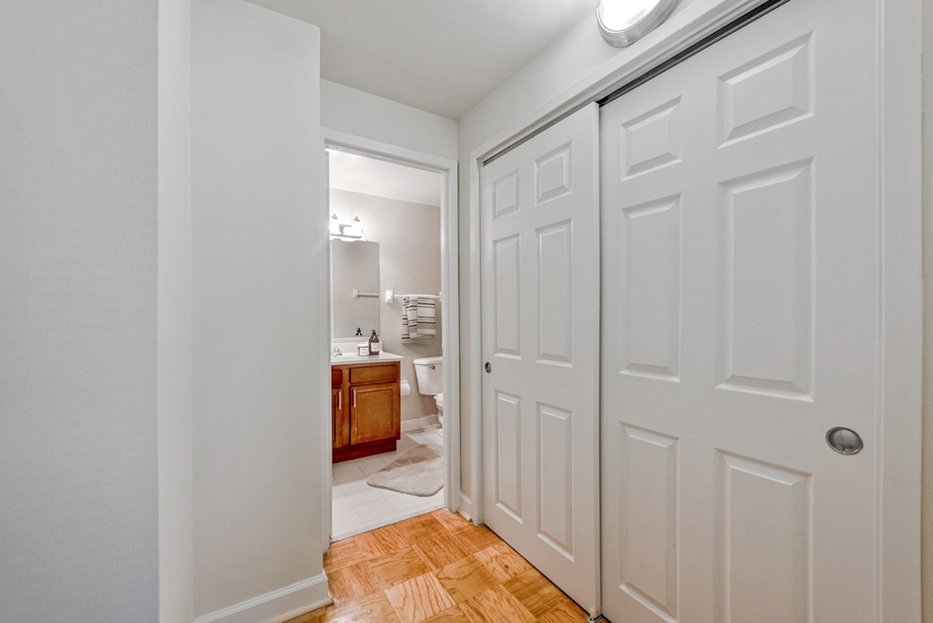 a bedroom with white closets and a bathroom with a toilet and sink