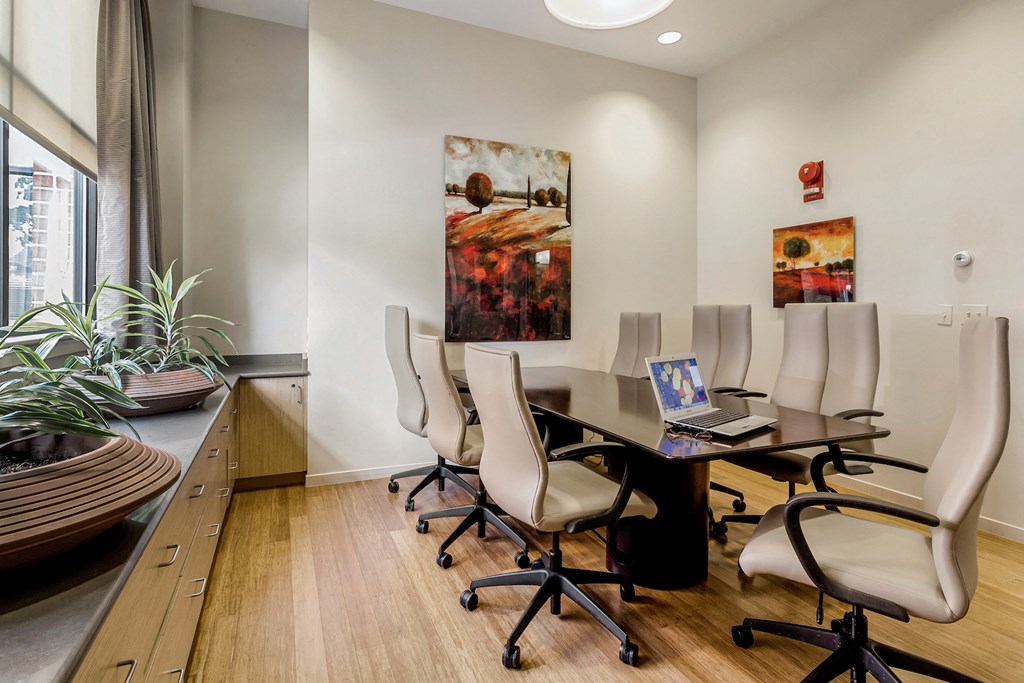 a conference room with a table and chairs and a laptop