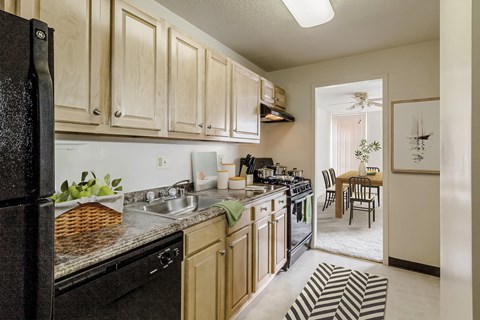 a kitchen with white cabinets and black appliances and a dining room with a table