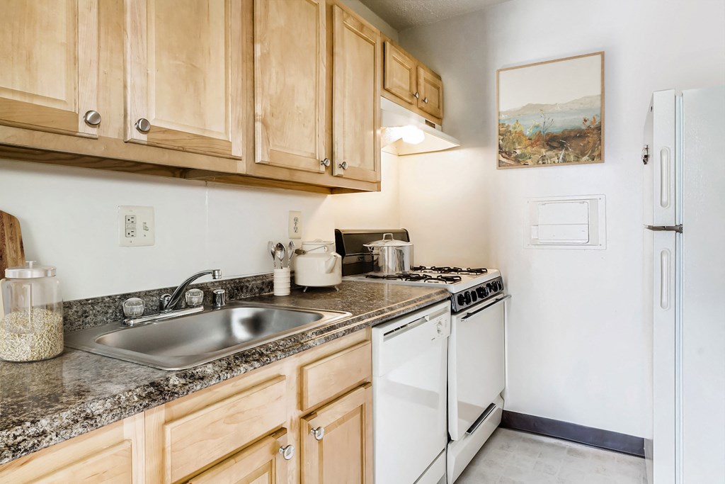 a kitchen with white appliances and granite counter tops and wooden cabinets