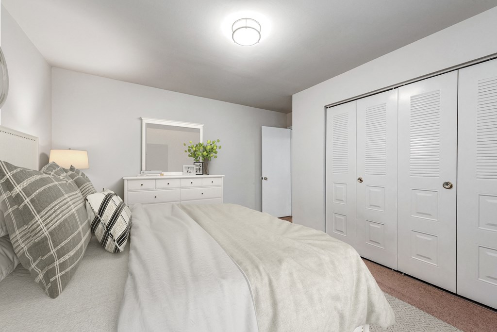 a white bedroom with a large bed and white closets