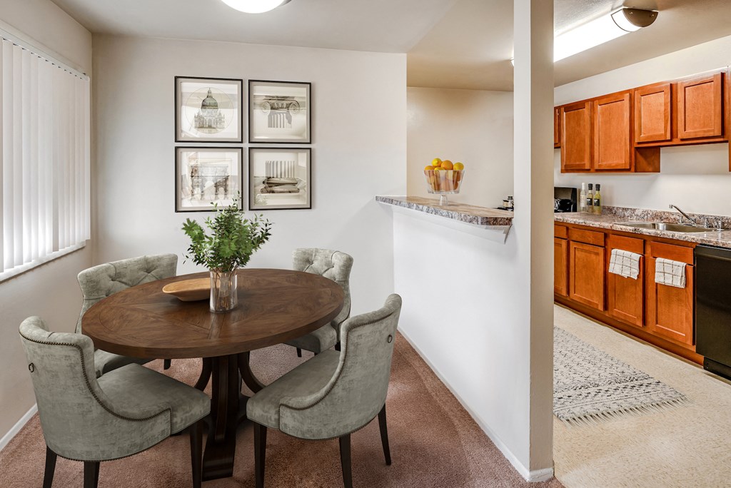 a dining room with a wooden table and chairs next to a kitchen