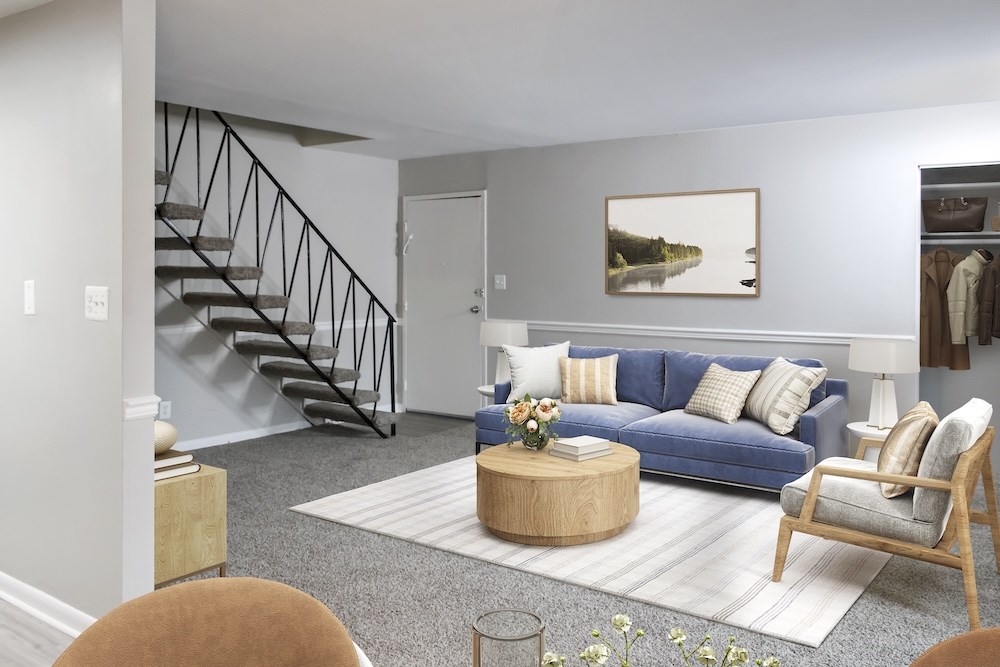 A living room with a blue couch, a coffee table, and a painting on the wall.