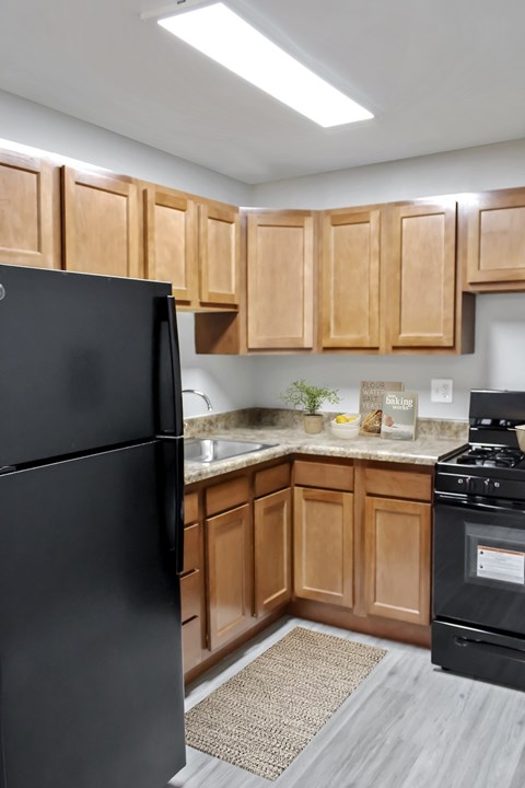 A black refrigerator stands in a kitchen with wooden cabinets.