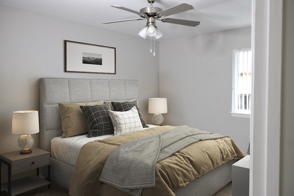 A bedroom with a bed, nightstands, and a ceiling fan.