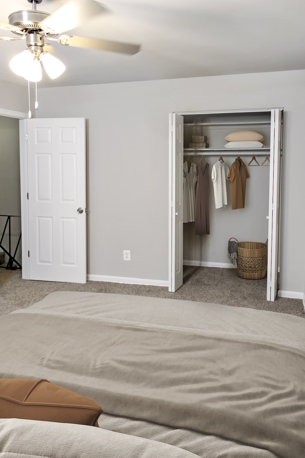 A bedroom with a bed, a ceiling fan, and an open closet.