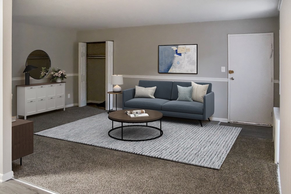 A living room with a grey couch and a round table.