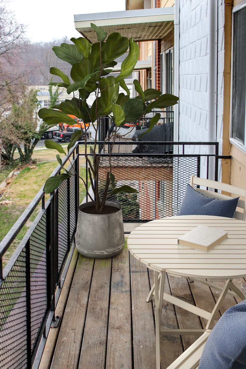 A balcony with a table and a potted plant.