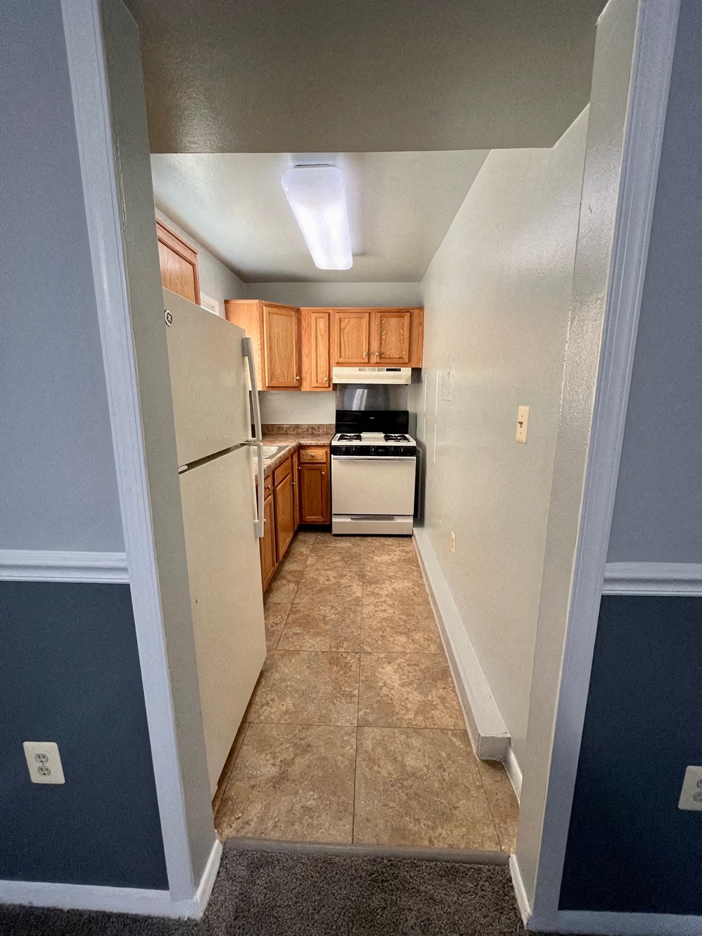 an empty kitchen with a refrigerator and a stove and