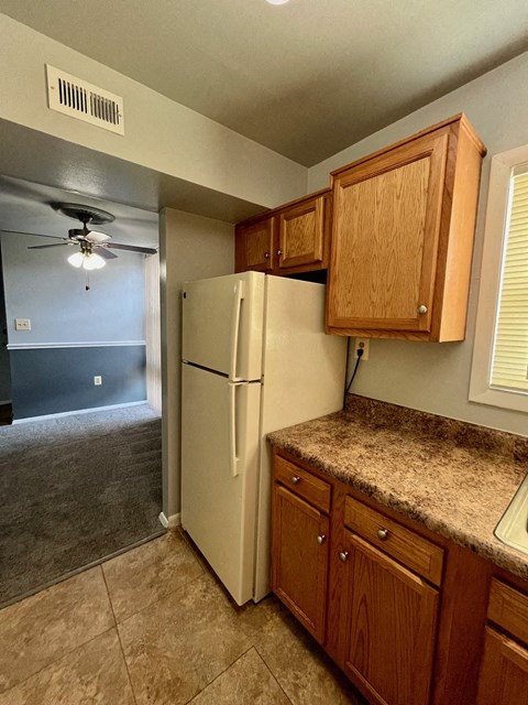 a kitchen with a refrigerator and wooden cabinets