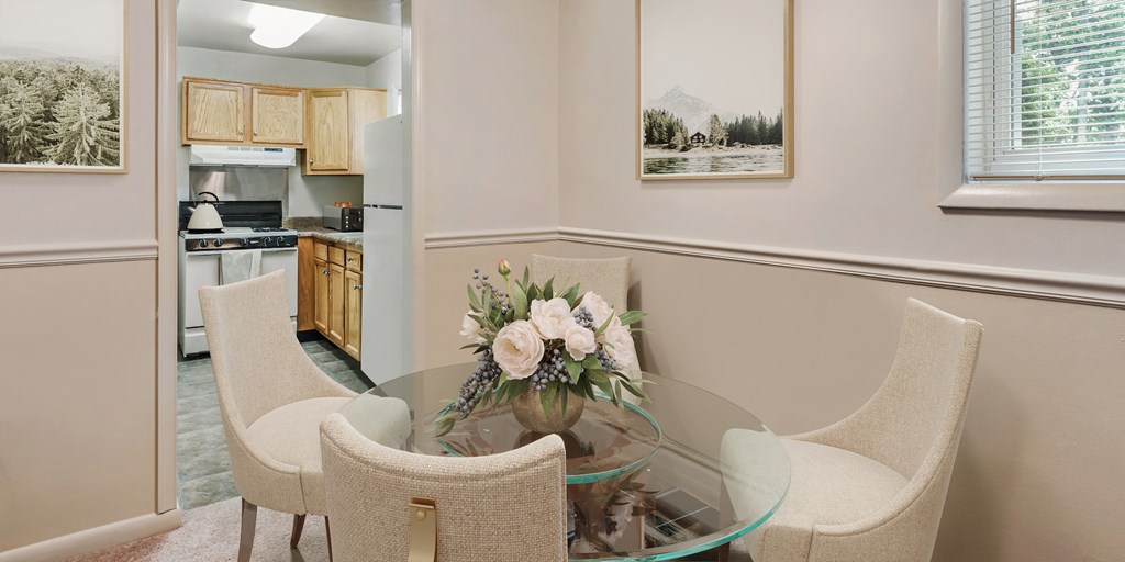 a dining room table with chairs and a vase of flowers