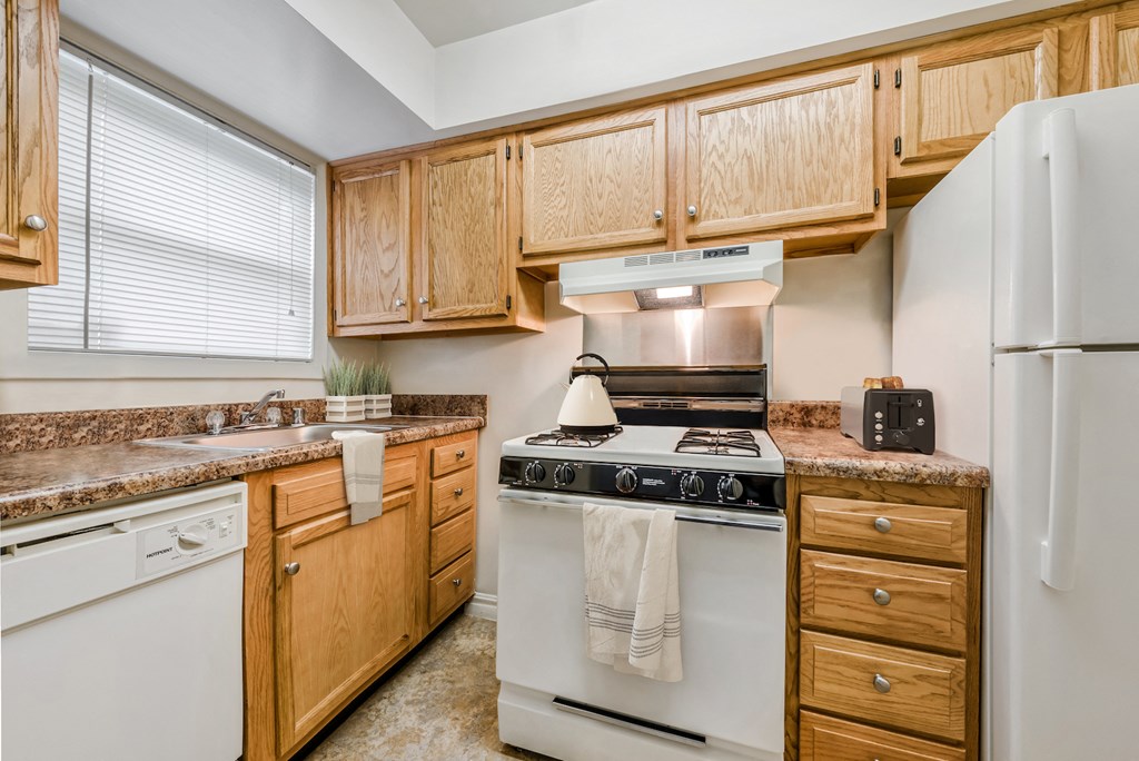 an updated kitchen with white appliances and wooden cabinets