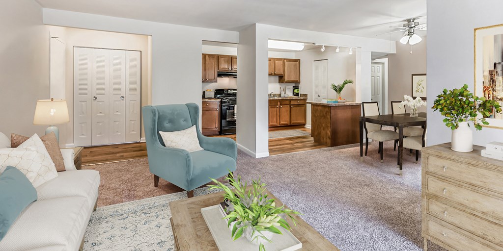 a living room and dining room with a kitchen in the background