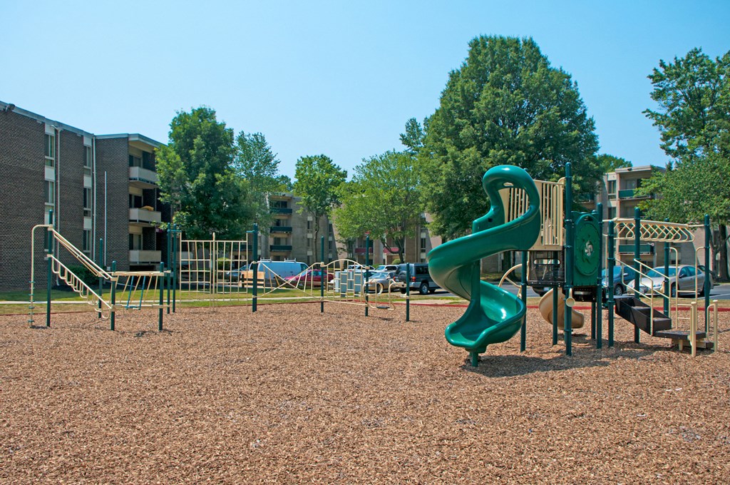 a playground with a green slide in a park