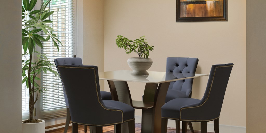 a dining room table with blue chairs and a potted plant