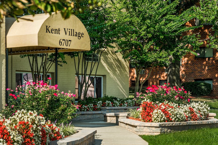 the front of the kent village 601 building with a sign and flowers