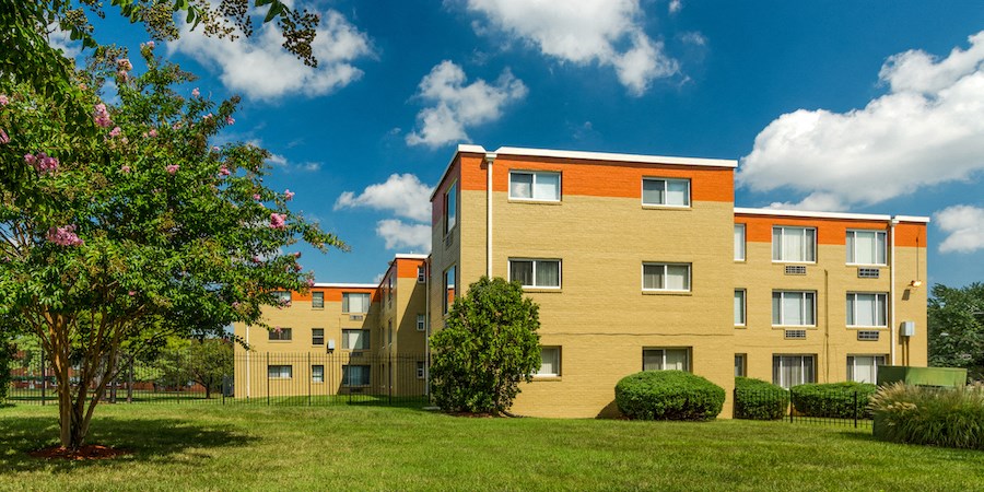 an apartment building with a green lawn and trees