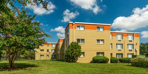 an apartment building with a green lawn and trees