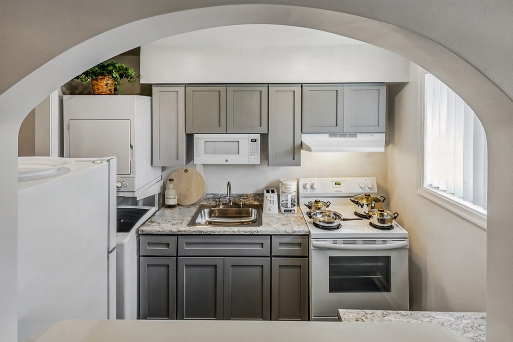 a kitchen with white appliances and gray cabinets