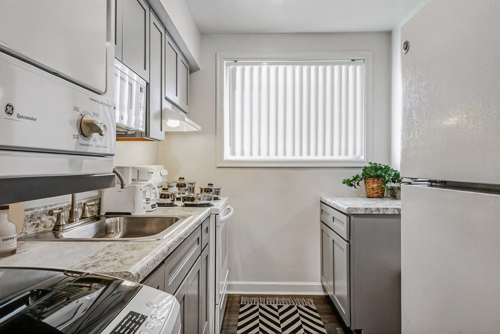 an all white kitchen with stainless steel appliances and a window