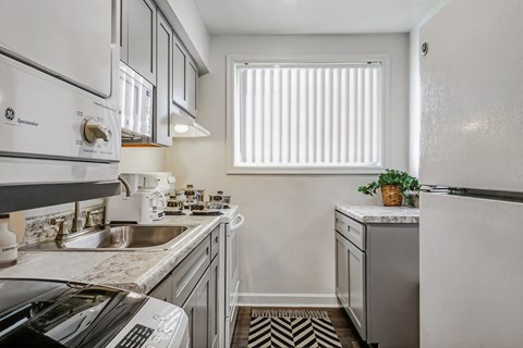 an all white kitchen with stainless steel appliances and a window