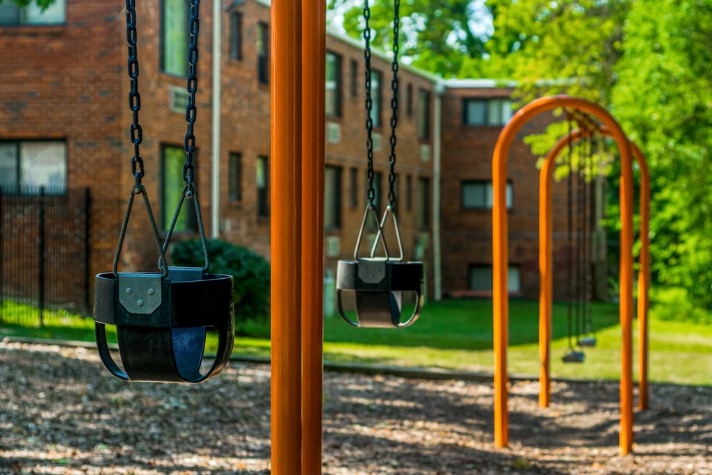 a playground with swings and a building in the background