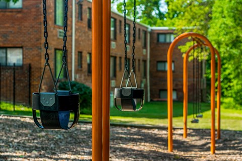 a playground with swings and a building in the background