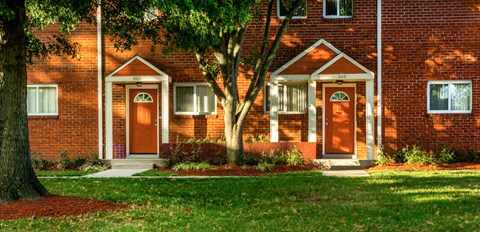 a red brick house with a tree in front of it