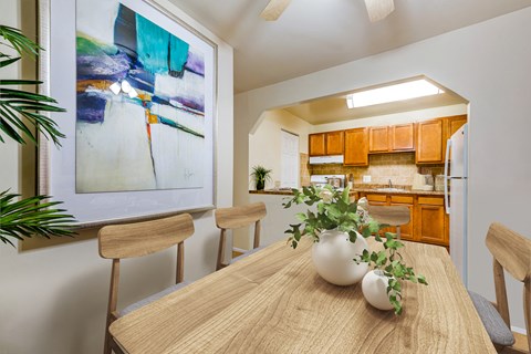 a dining room table with a vase on top of it next to a kitchen