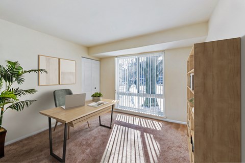 a home office with a large window and a desk with a laptop