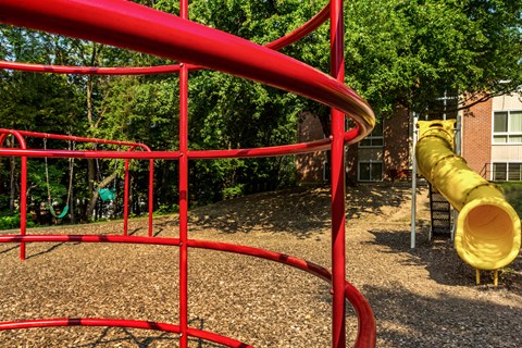 a playground with a yellow slide and red bars