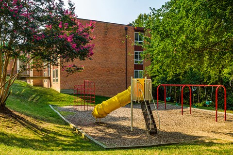 a playground with a large yellow slide in front of a building