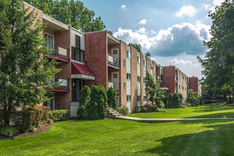 a row of brick apartment buildings with green grass and trees