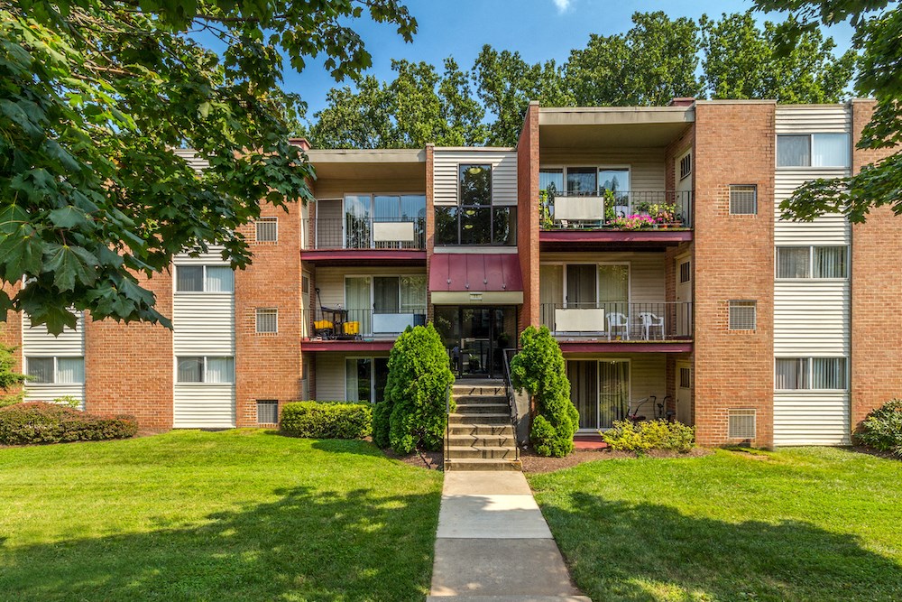 exterior view of an apartment building with green grass and trees